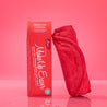 Rolled up Love Red MakeUp Eraser cloth next to packaging.