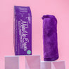 Rolled up Queen Purple MakeUp Eraser next to packaging, both propped up on platforms.