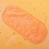 Juicy Orange MakeUp Eraser laying flat surrounded by waterdrops.