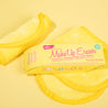 Mellow Yellow MakeUp Eraser packaging on top of a folded Mellow Yellow MakeUp Eraser cloth.