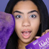 Woman holding up Queen Purple MakeUp Eraser cloth and packaging. 