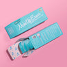 Front of Fresh Turquoise MakeUp Eraser packaging next to the back of Fresh Turquoise MakeUp Eraser packaging. The back of the packaging is open with a rolled-up Fresh Turquoise MakeUp Eraser peeking out.